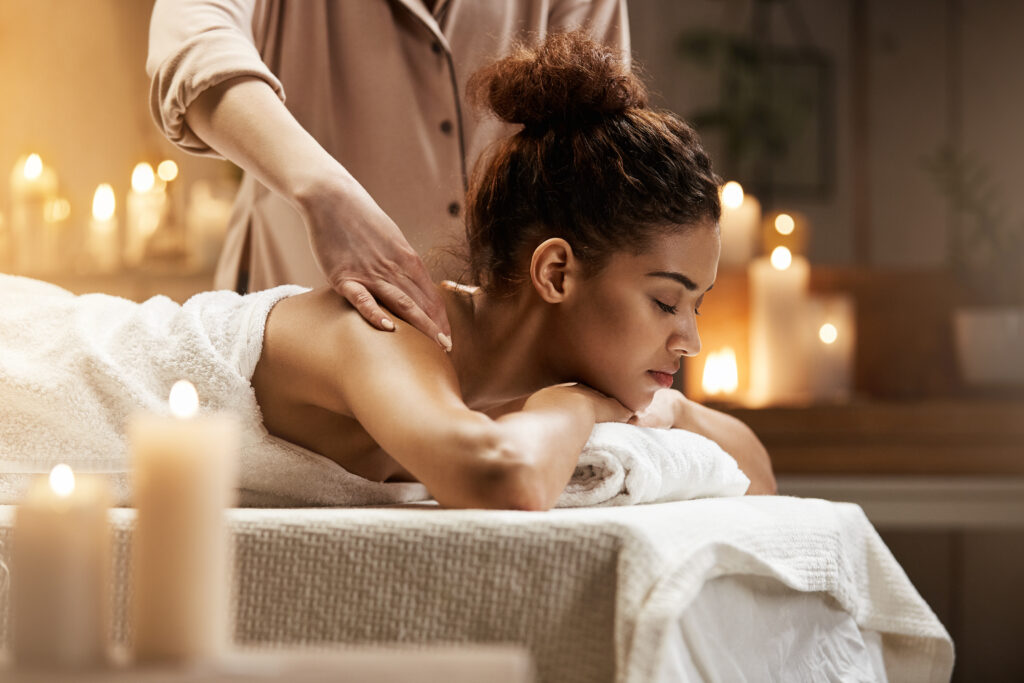 tender african girl smiling enjoying massage with closed eyes in spa resort.